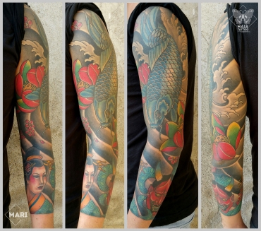 Fotografia di un braccio maschile con tatuaggio in stile giapponese raffigurante una carpa, un viso di geisha, un demone e fiore di loto eseguito da Marianna Bevilacqua presso il Maia Tattoo di Milano Cornaredo