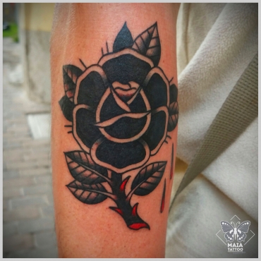 Fotografia di un avambraccio di uomo con tatuata una rosa nera in stile tradizionale, eseguita da Alessandro Paparella nello studio Maia Tattoo di Milano Cornaredo