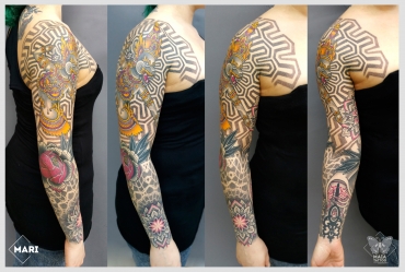 Fotografia di un tatuaggio su un intero braccio, in stile ornamentale e dotwork raffigurante una dea lupa thailandese , un mandala, un amuleto con sfondi a texture e pattern geometrici 